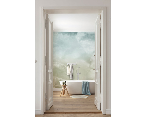 Baie luminoasă cu cadă, taburet și tapet cu model de nori, vedere printr-o ușă deschisă.