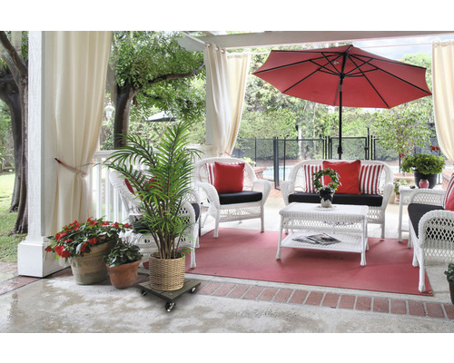 Scenă de terasă cu mobilier de răchită alb, umbrelă de soare roșie și plante în ghivece