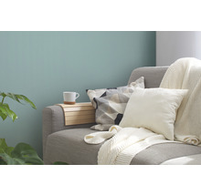 Cameră de zi decorativă cu canapea, perne, pled, raft din lemn și cană