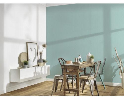 Sufragerie cu masă din lemn, scaune și raft de perete cu decorațiuni în fața unui perete colorat