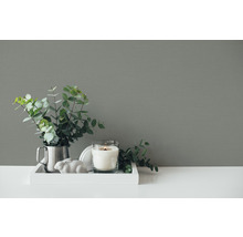 Aranjament decorativ cu lumânare, plantă și figurină decorativă pe o tavă.