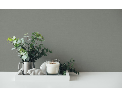 Aranjament decorativ cu lumânare, plantă și figurină decorativă pe o tavă.