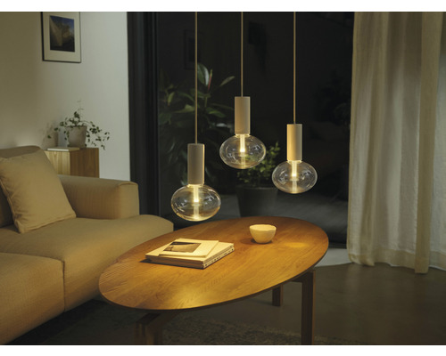 Sufragerie cu canapea, masă din lemn și trei lămpi suspendate cu becuri