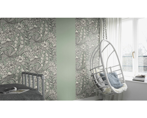 Cameră cu tapet cu model floral, pat și scaun suspendat