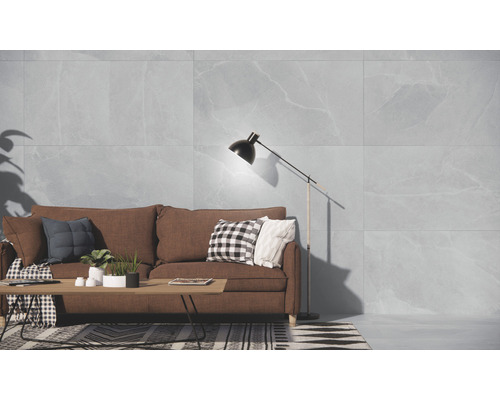 Cameră de zi luminoasă cu canapea, masă, lampă de podea și perete cu gresie