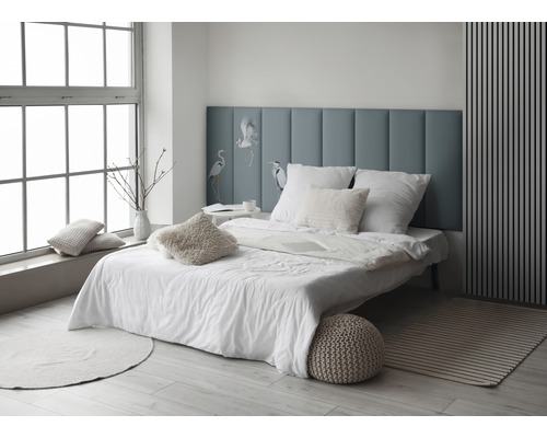 Dormitor luminos cu pat, perne și tăblie albastră cu motiv de pasăre