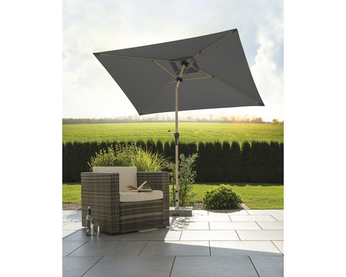 Umbrelă de grădină pătrată lângă fotoliul de răchită pe terasă