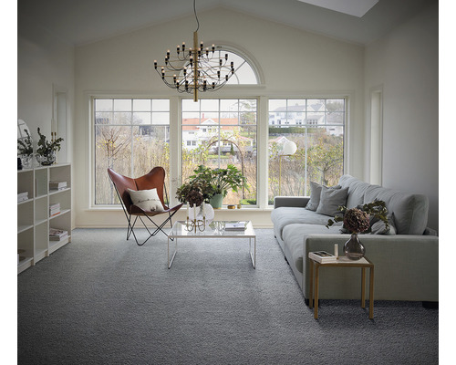 Living luminos cu mochetă gri, canapea, fotoliu și ferestre