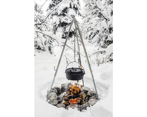 Cazan deasupra unui foc de tabără pe un trepied în zăpadă