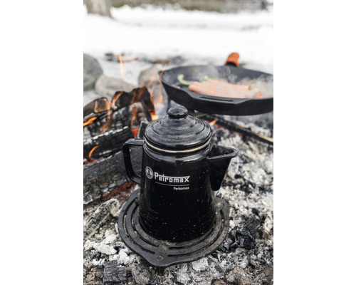 Cafetiera cu percolator Petromax pe un grătar la foc de tabără cu tigaie