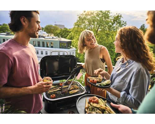 Persoane care fac grătar cu un grătar portabil pe un balcon