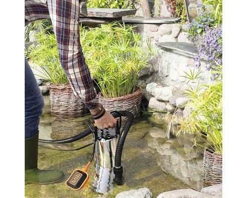 Bărbat cu pompă submersibilă de la Black plus Decker în iaz de grădină