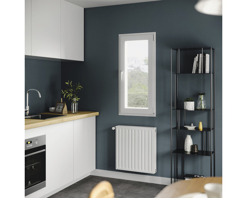 Scenă de bucătărie cu dulapuri albe, chiuvetă, fereastră, radiator și raft.