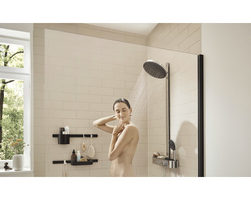 Duș cu paravan de duș, cap de duș și rafturi de perete într-o baie luminoasă.