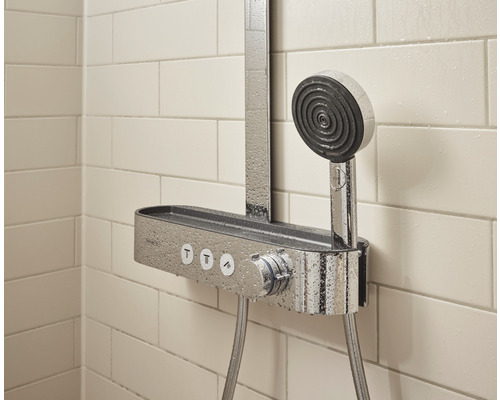 Sistem de duș cu duș de mână și raft în fața unui perete placat cu faianță