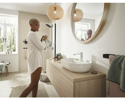 Baie modernă cu lavoar, oglindă rotundă și iluminare naturală