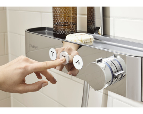 Prim-plan cu o mână care apasă un buton de pe o baterie de duș cu raft