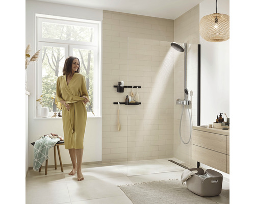 Baie luminoasă cu duș, raft de depozitare și femeie în halat de baie