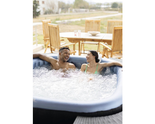 Un cuplu se relaxează într-un jacuzzi gonflabil în aer liber.