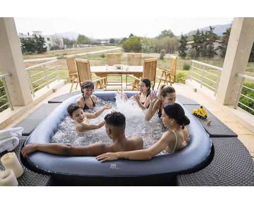 Un grup de persoane se bucură de o cadă cu hidromasaj afară, pe o terasă cu mobilier de grădină.