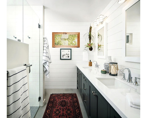 Baie luminoasă cu lavoar dublu, oglinzi, fereastră și decorațiuni.