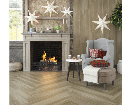 Cameră de zi cu șemineu, fotoliu, taburet și pardoseală din gresie cu aspect de lemn în model herringbone