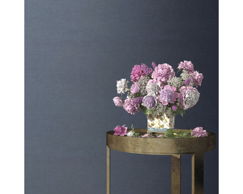 Aranjament floral decorativ într-o vază pe o măsuță laterală în fața unui perete texturat