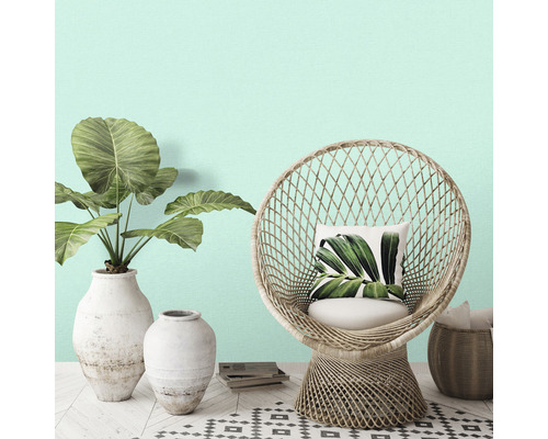 Scenă decorativă cu fotoliu din ratan, plante în vaze și covor cu model