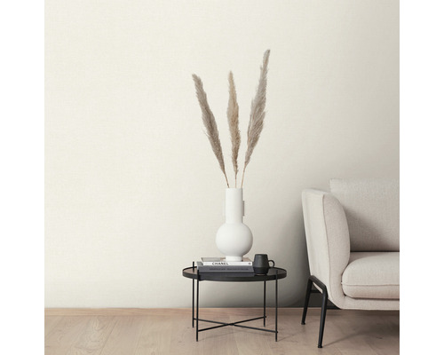 Pene decorative într-o vază albă pe o măsuță neagră lângă o canapea