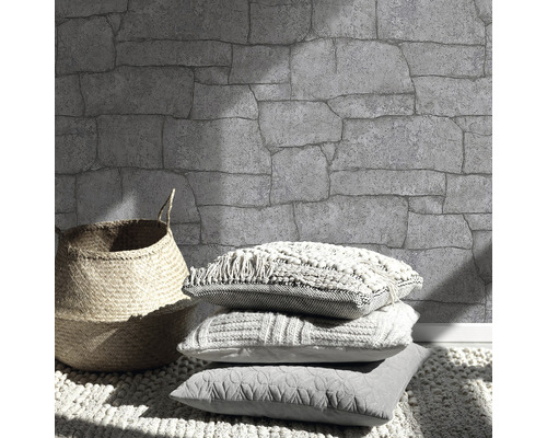 Perete cu model de piatră, coș și perne pe un covor.