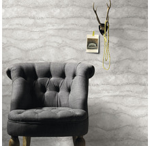 Fotoliu gri în fața unui tapet cu model ondulat, cu coarne de cerb deasupra