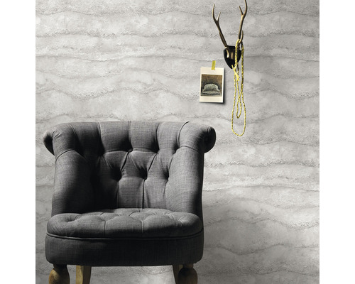 Fotoliu gri în fața unui tapet cu model ondulat, cu coarne de cerb deasupra