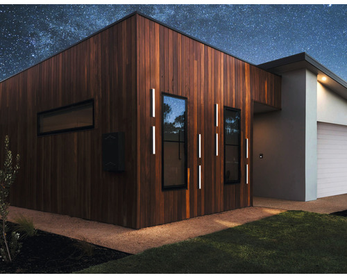 Casă modernă cu placare din lemn, iluminat exterior și cer înstelat.