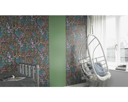 Cameră decorată cu tapet cu model floral, balansoar și pat.