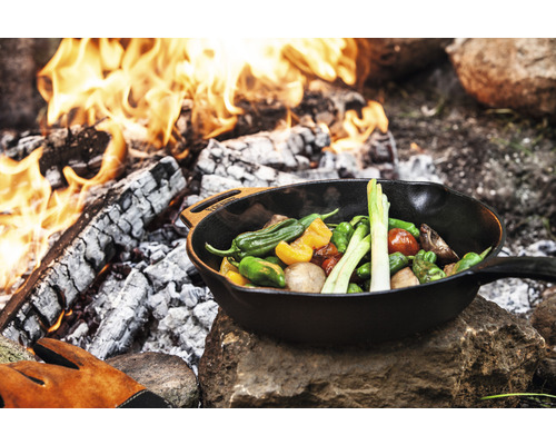 Legume gătite într-o tigaie de prăjit deasupra unui foc deschis