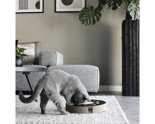 Pisică lângă o piesă de mobilier zgâriabilă rotundă din carton ondulat într-o sufragerie