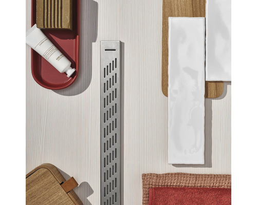 Scenă de baie cu rigolă de duș, săpun, cremă de mâini și faianță