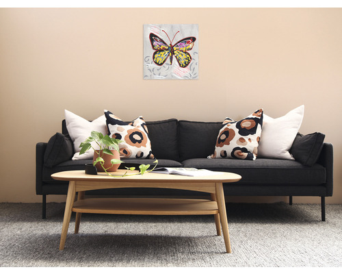 Living cu canapea, măsuță de cafea și un tablou cu un motiv de fluture pe perete.