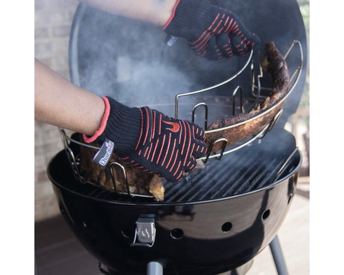 Persoană cu mănuși de grătar așază suportul pentru coaste cu coaste pe grătarul cu cărbune