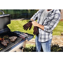 Bărbat care își pune mănușile de grătar în fața grătarului