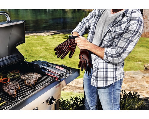 Bărbat care își pune mănușile de grătar în fața grătarului