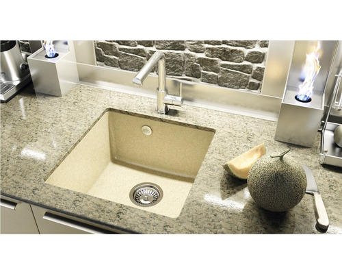 Chiuvetă de bucătărie din piatră turnată cu robinet și pepene galben pe blat.