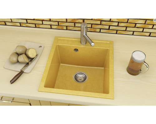 Chiuvetă cu robinet pe un blat cu tocător, cartofi, cuțit și halbă de bere.