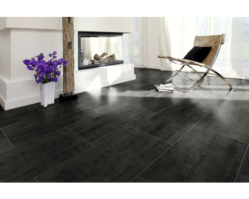 Cameră de zi cu gresie închisă la culoare, șemineu și fotoliu.