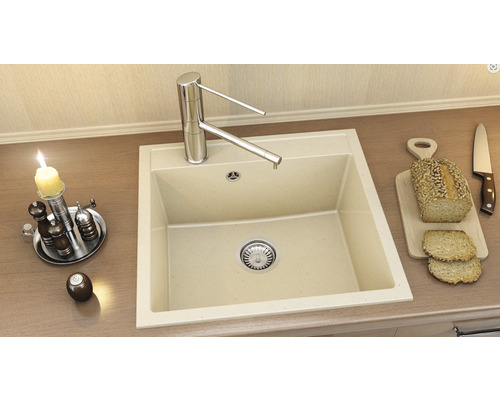 Chiuvetă cu robinet, dozator, condimente, lumânare, pâine și cuțit pe un blat de bucătărie