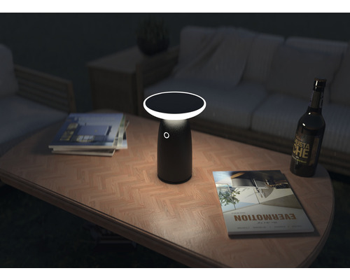 Scenă cu o lampă de masă pe o măsuță de cafea cu reviste și o sticlă de bere