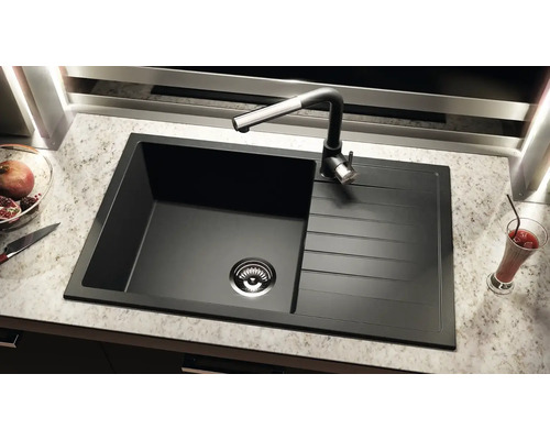 Chiuvetă neagră cu picurător și robinet pe un blat de bucătărie.