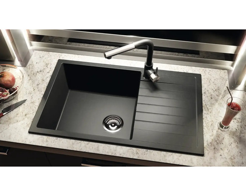 Chiuvetă neagră cu picurător și baterie pe un blat de bucătărie.