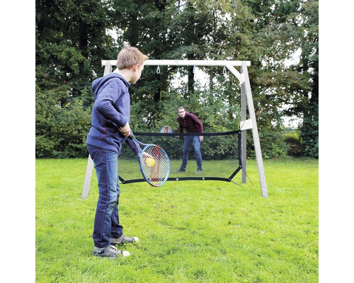 Două persoane joacă tenis cu o plasă de tenis în grădină.