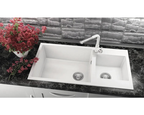 Chiuvetă albă cu două cuve și baterie pe blat de lucru închis la culoare